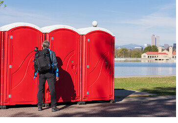 Portable restrooms placed along a lakefront path in the city, with the skyline visible in the background