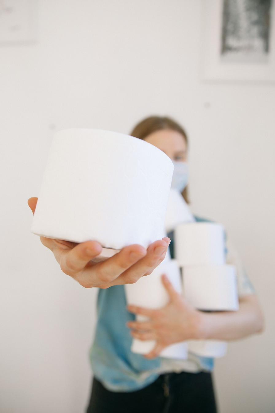 Hand holding a fresh stack of toilet paper rolls, representing restocked hygiene supplies