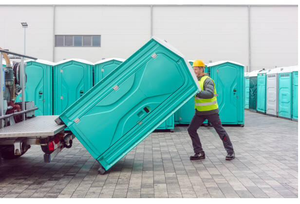 Crew member delivering a portable toilet unit to a construction site
